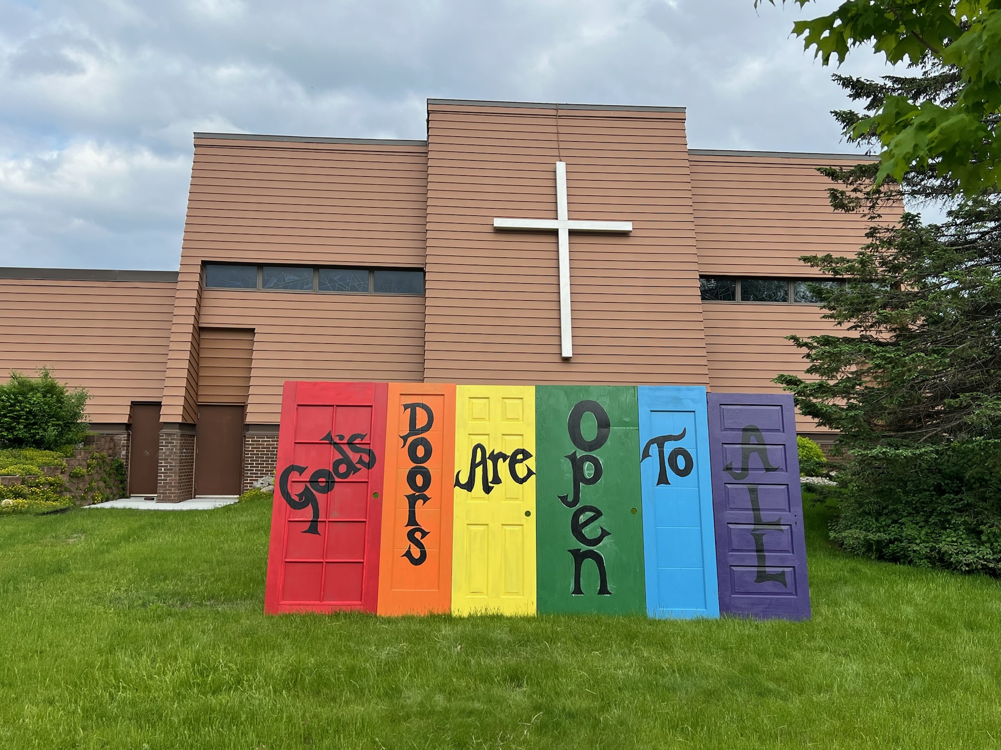 Rainbow painted doors with the text "God's Doors are Open to All"